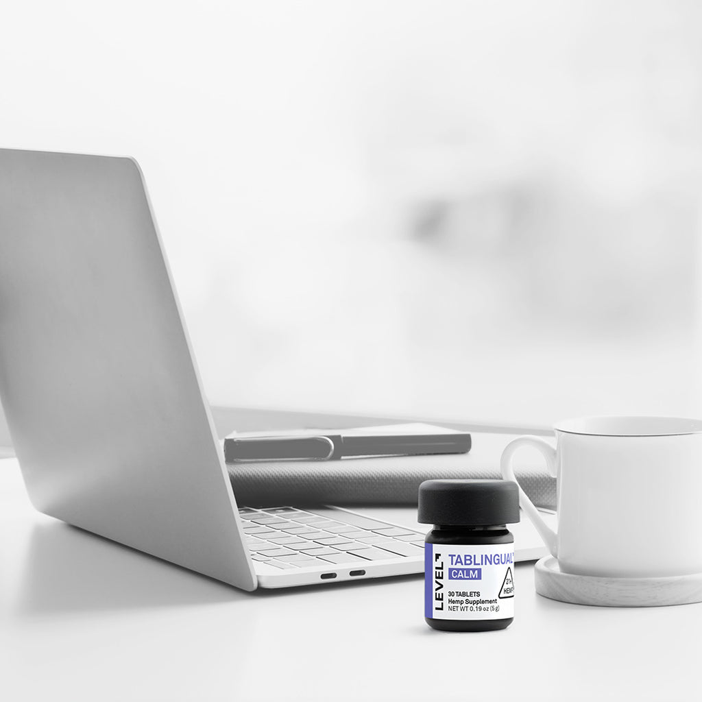 Laptop with a bottle of 'Level' supplements on a white surface
