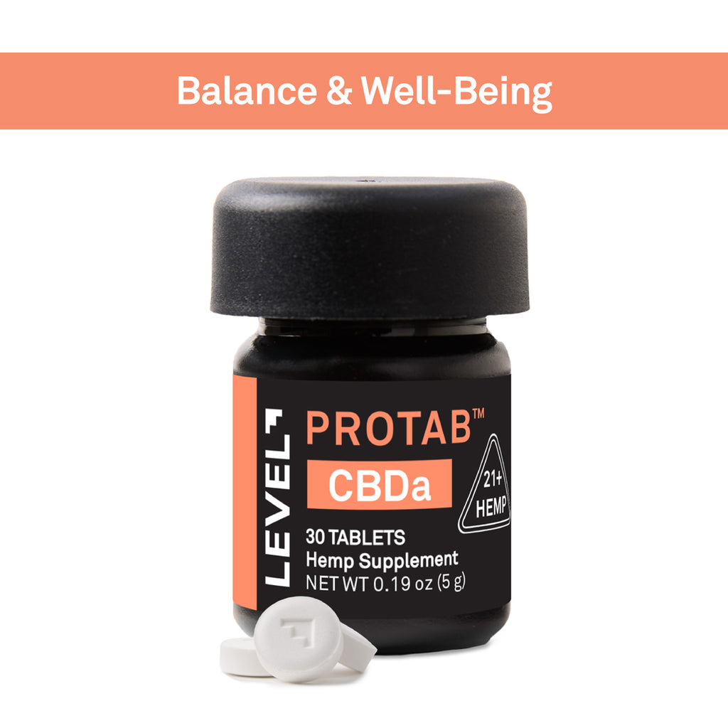 A small black bottle of Level 7 Protab CBDa hemp supplement with a black cap, shown on a white background with an orange banner reading 'Balance & Well-Being' at the top. Two white tablets are placed in front of the bottle.