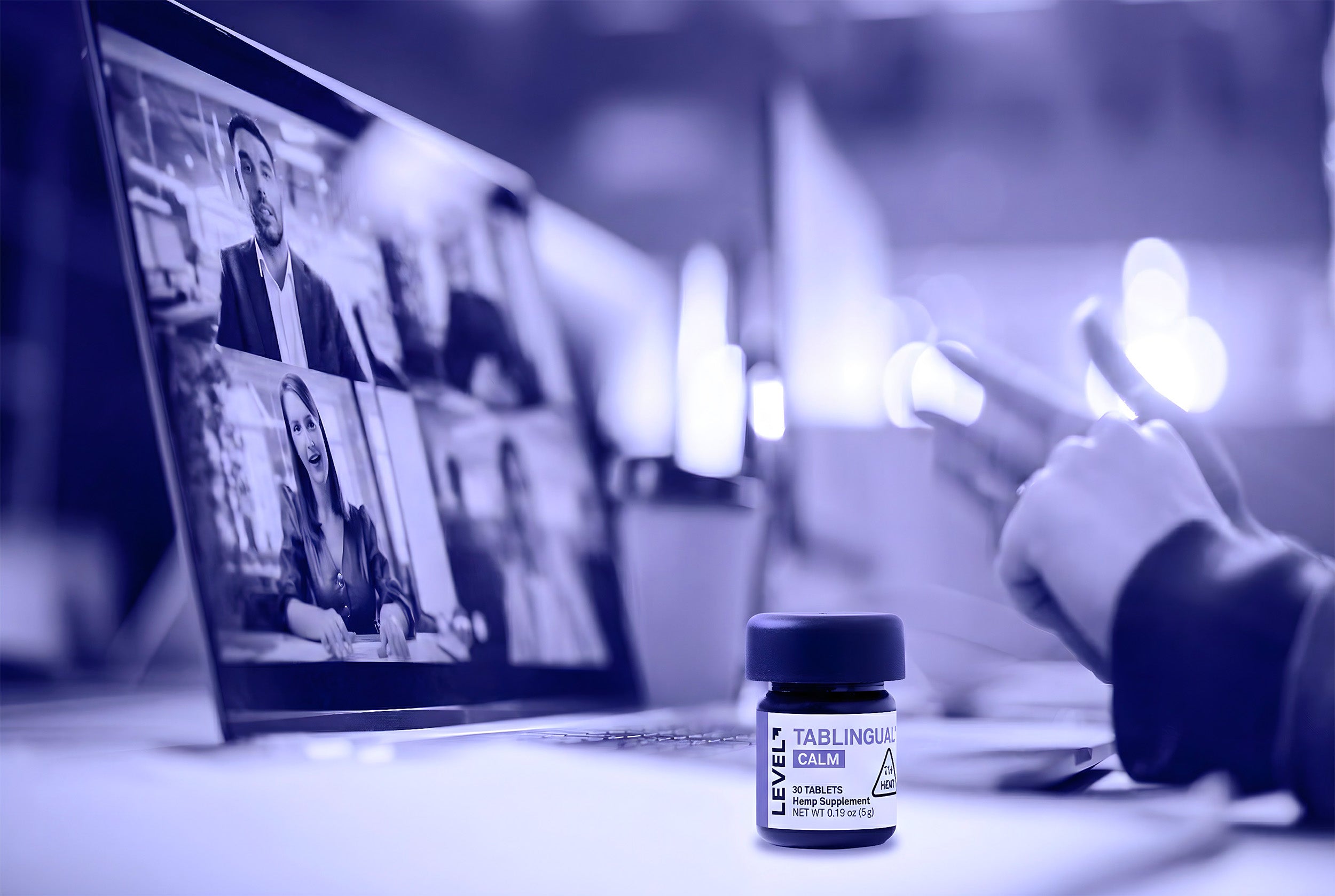 Laptop displaying a video call with a bottle of Level tabs on a desk.